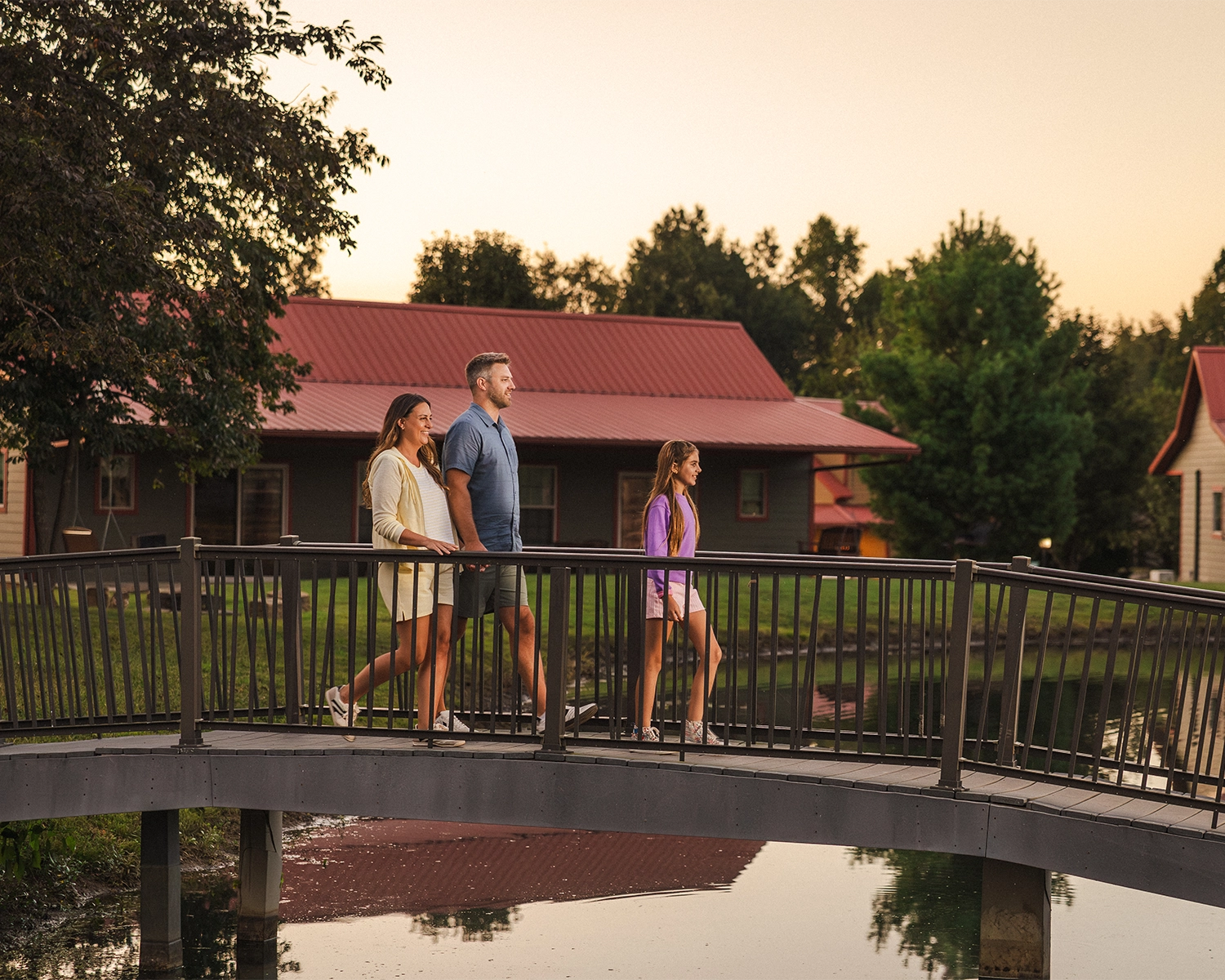 A family walks across a bridge over one of the lakes at Santa's Cottages in Santa Claus, Indiana.